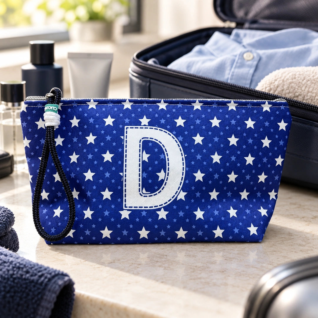 Bolsa Alex azul com letra D fechada num cenário de viagem com mala, roupa e artigos de higiene masculina.