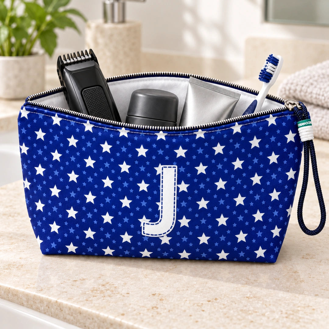 Bolsa Alex azul com letra J aberta, com produtos de higiene masculina, interior branco e fecho metálico.