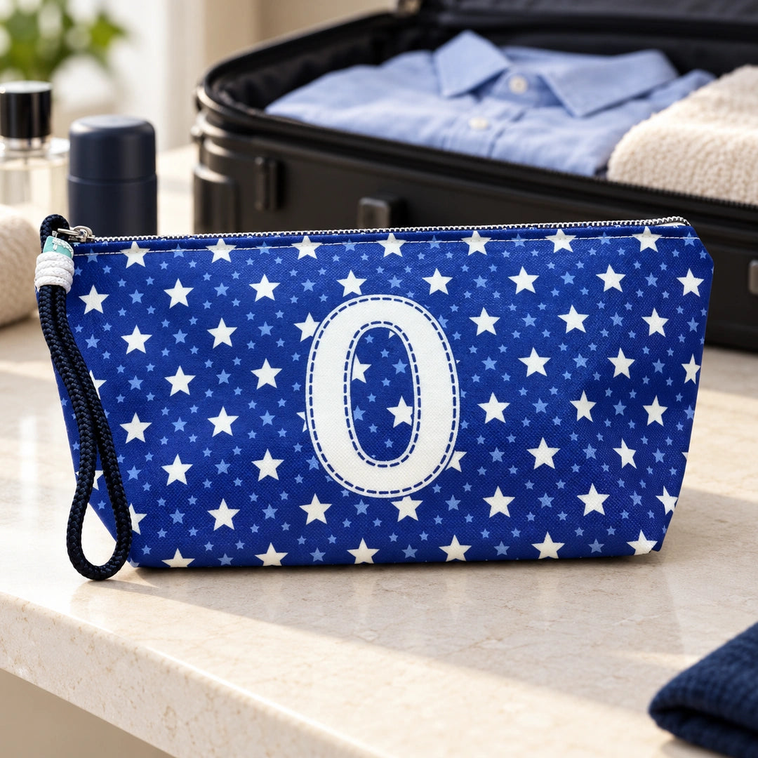 Bolsa Alex azul com letra O fechada num cenário de viagem com mala, roupa e artigos de higiene masculina.