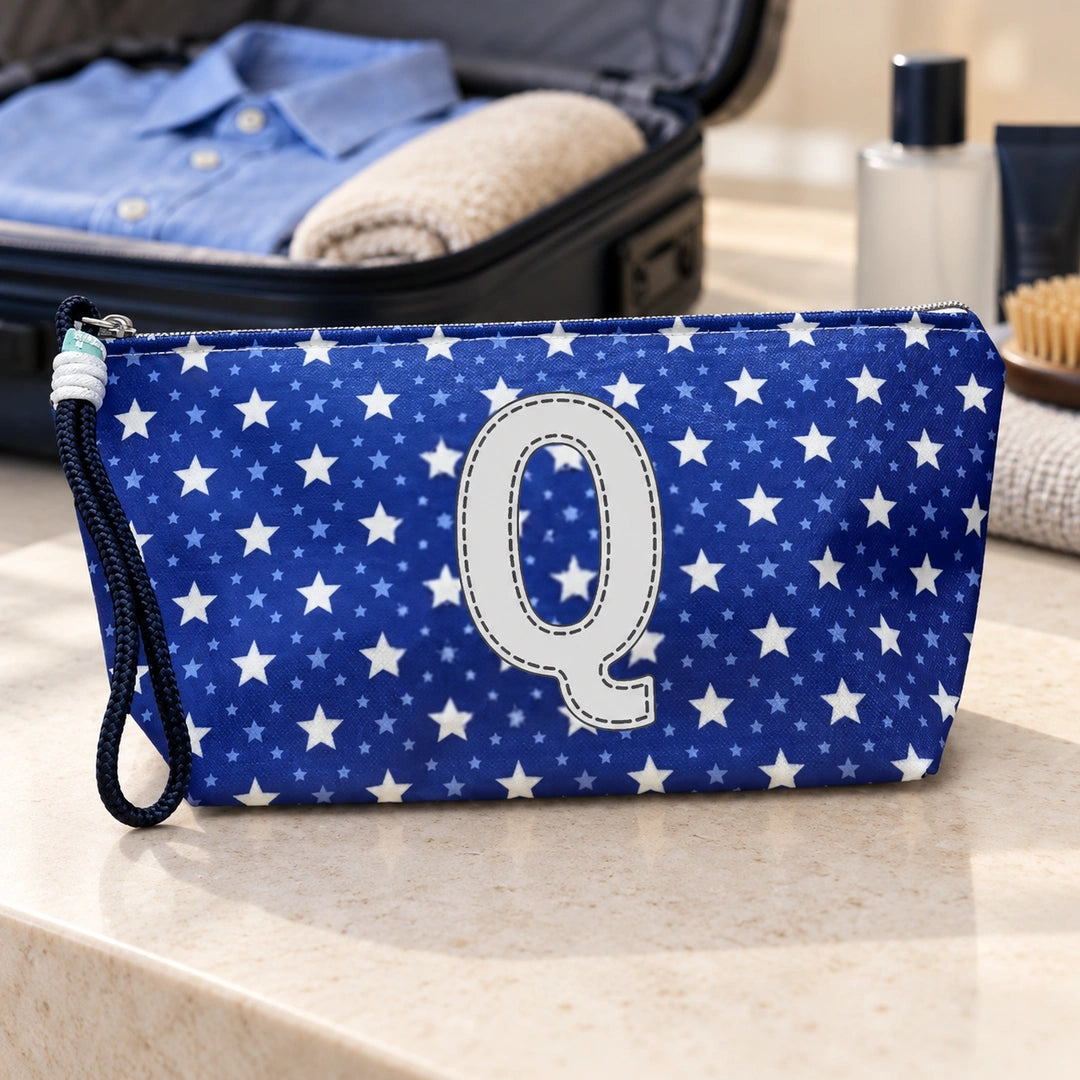 Bolsa Alex azul com letra Q fechada num cenário de viagem com mala, roupa e artigos de higiene masculina.