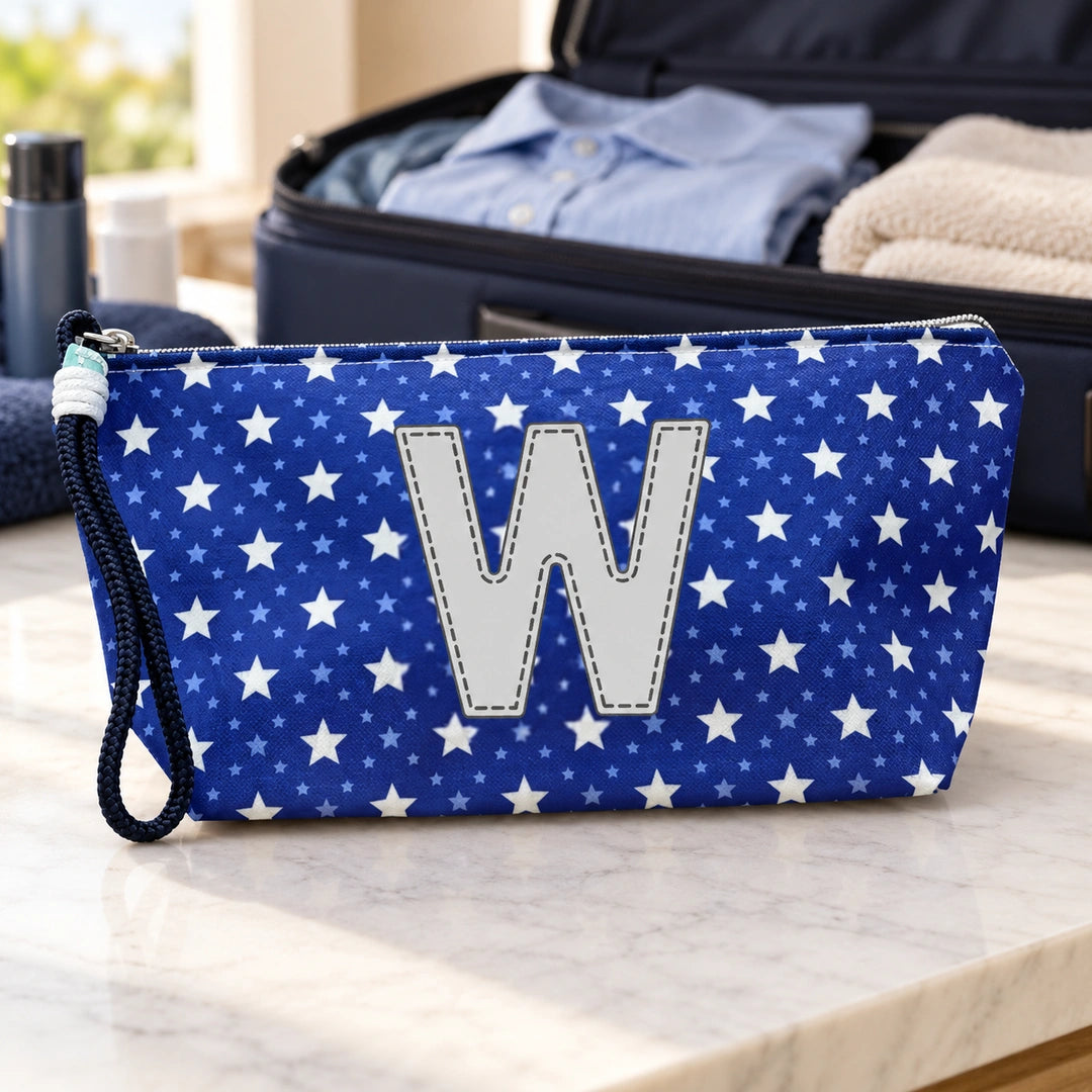 Bolsa Alex azul com letra W fechada num cenário de viagem com mala, roupa e artigos de higiene masculina.