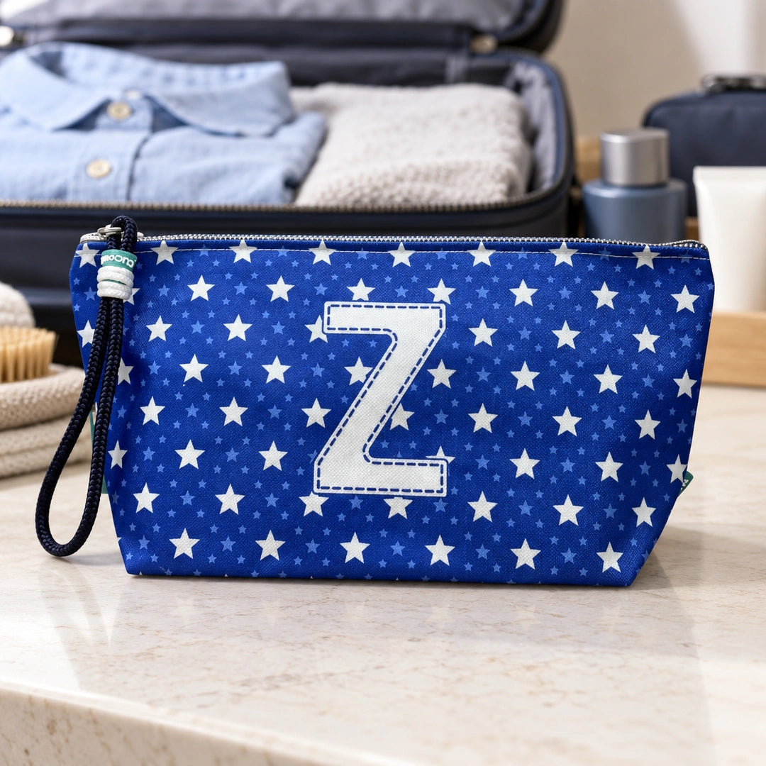 Bolsa Alex azul com letra Z fechada num cenário de viagem com mala, roupa e artigos de higiene masculina.