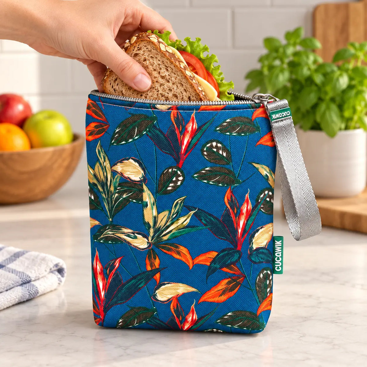 Bolsa isotérmica para snacks Folhas Exóticas Azul Petróleo em utilização – com snacks no interior