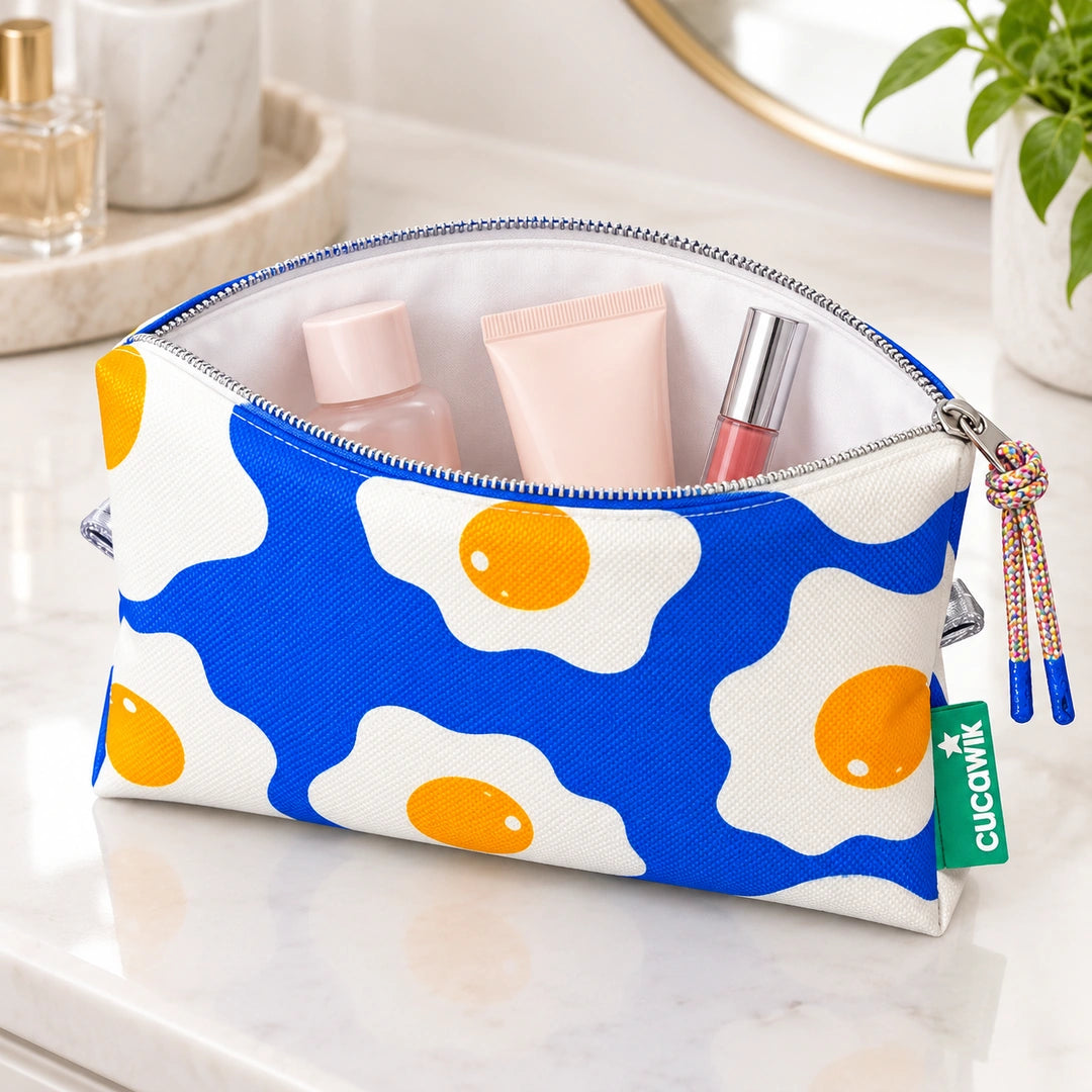 Necessaire Médio Impermeável Eden Ovos Estrelados Azul — aberta com cosméticos
